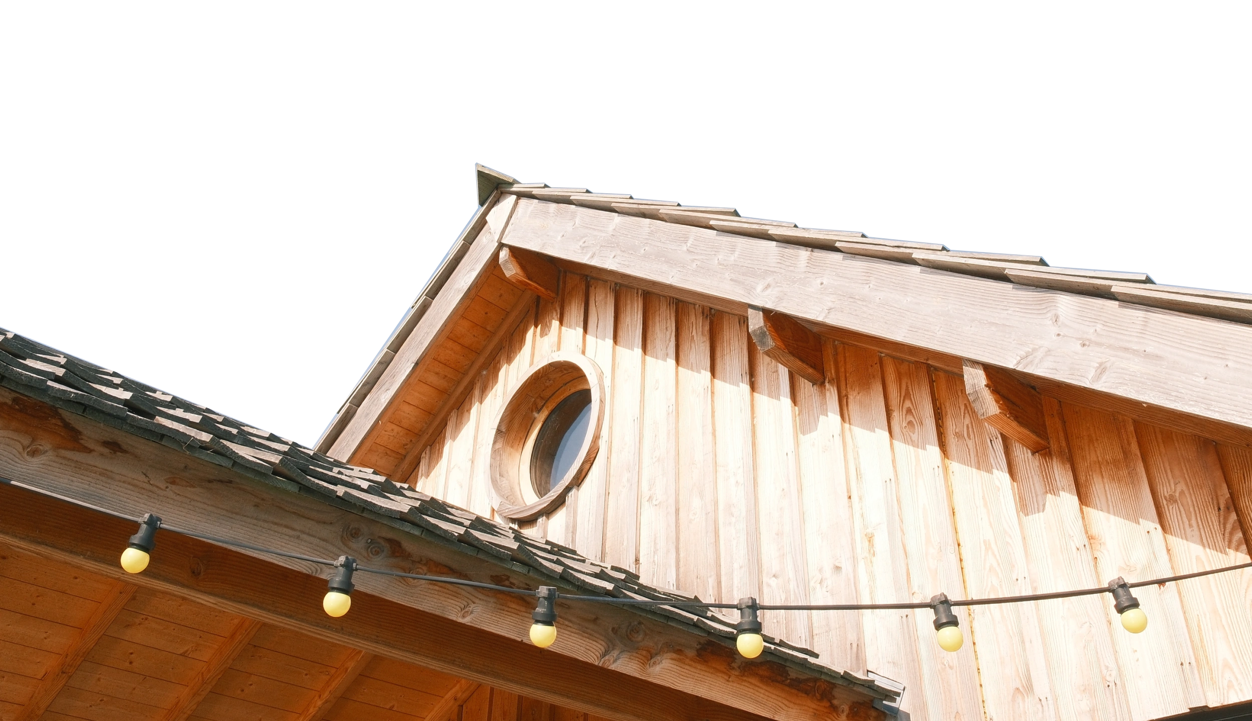 Pignon en bois d'une cabane avec œil-de-bœuf et guirlande d'ampoules