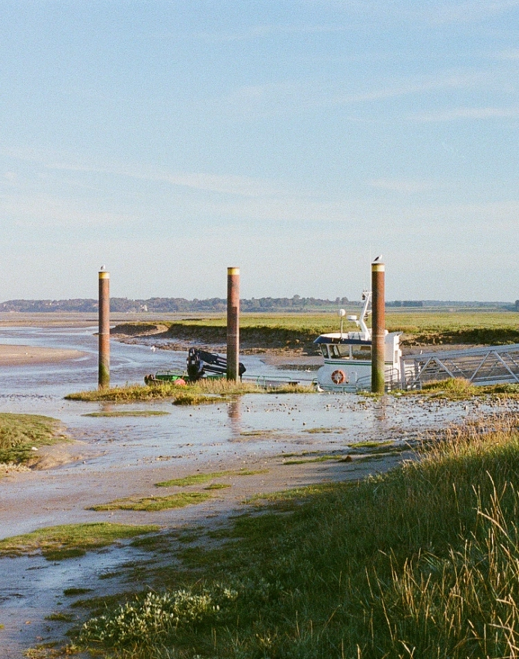 Baie à marée basse avec bornes d'amarrage et bateau échoué